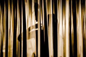 Artistic image of stand up base player through stage curtains