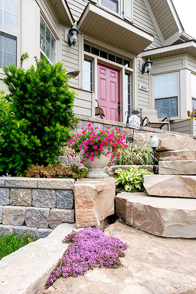 Front landscaping of New Amherst Home with stone, flowers and red door