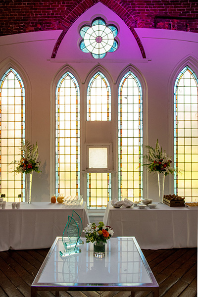 Tables with flowers and awards sit in front of the church windows