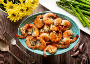 Food Photograph of grilled shrimp on a blue oval plate with asparagus on the side from above.