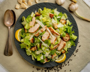 Chicken Caesar Salad from above on round slate plate