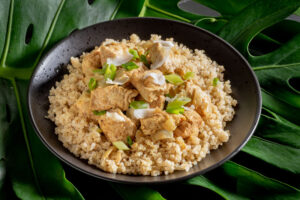 Food photograph of Curry Chicken on Qinoa in black bowl.