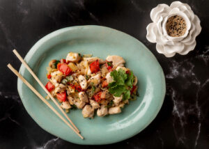 Ginger Chicken Stir Fry with red pepper and onion on green oval plate