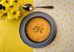 food photograph of red lentil soup in a blue bowl from above.